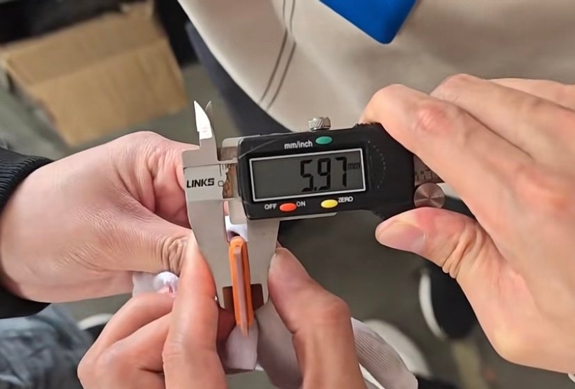 Digital caliper measuring the dimensions of a copper busbar